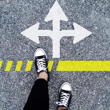 some feet on a grey pavement, with a white arrow